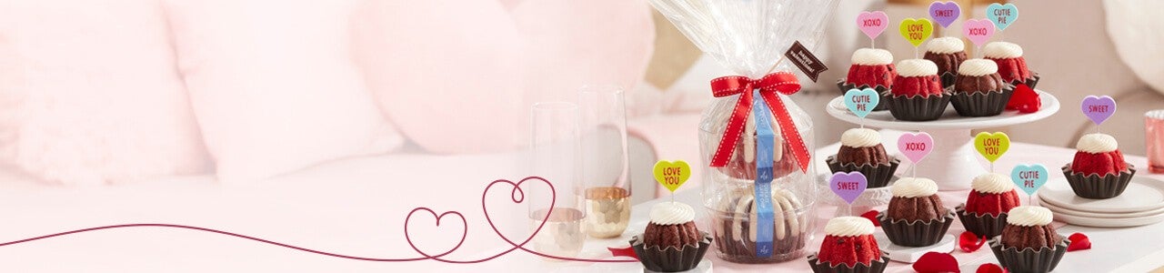 Festive Bundtini toppers featuring different color hearts and sayings, and Bundtlet Tower with two Bundtlets wrapped in cellophane tie with a ribbon