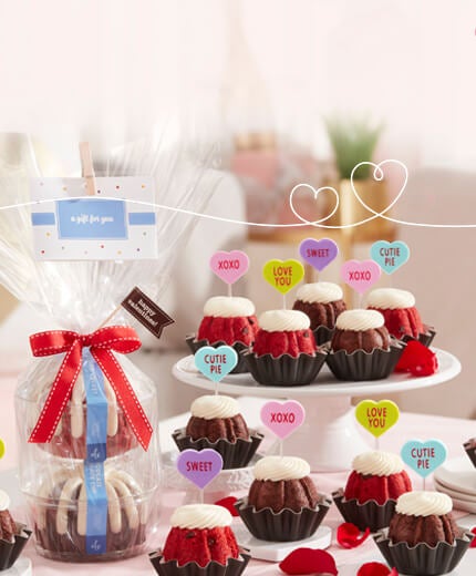 Festive Bundtini toppers featuring different color hearts and sayings, and Bundtlet Tower with two Bundtlets wrapped in cellophane tie with a ribbon