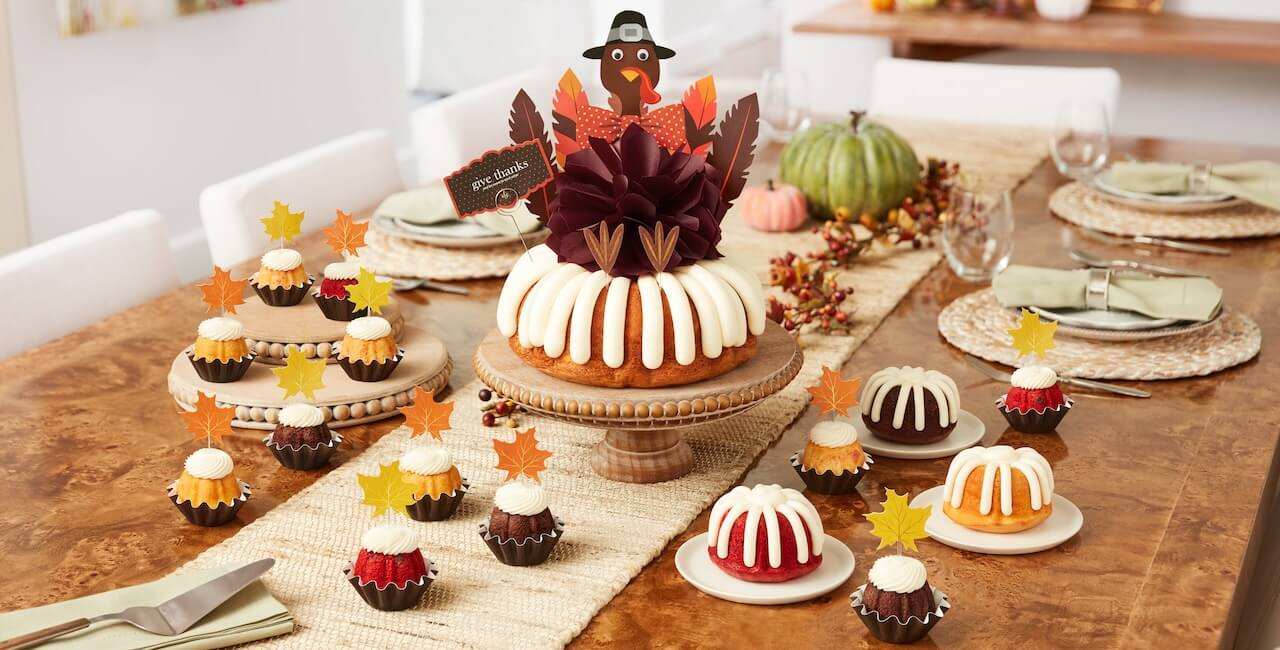 Assorted bundt bundtinis with cream cheese frosting, displayed with fall leaves decorations.