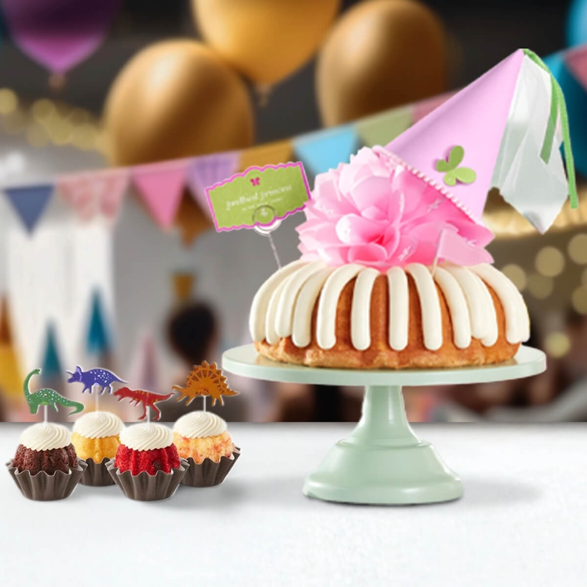 Assorted Bundtinis with dinosaur toppers and princess cake with pink hat and bow