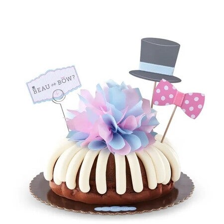 Gender reveal Bundt Cake with frosting, blue and pink tissue puff, top hat, bow tie, and Beau or Bow sign.
