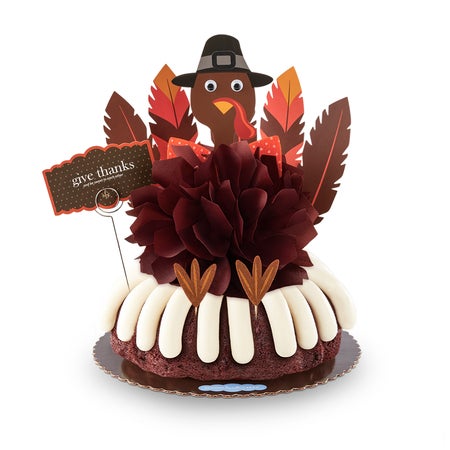 A large bundt cake with a chocolate colored bow in the center and a whimsical turkey cutout with 5 Gratitude Feathers.