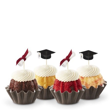 Four graduation Bundtinis in a variety of flavors with cream cheese frosting and graduation cap toppers for graduation parties.