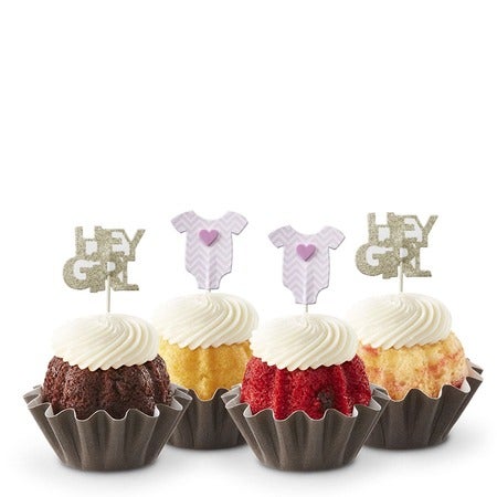 Four baby shower Bundtinis in variety of flavors with frosting and pink Hey Girl themed toppers for girl baby shower.