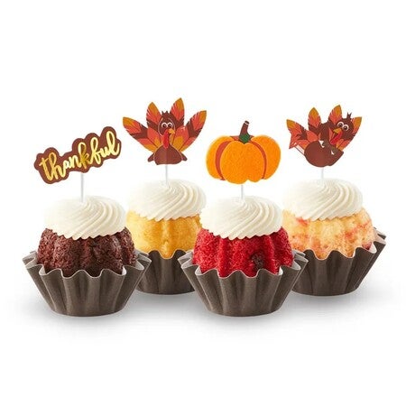 Assorted mini bundt cakes with turkey decorations, a pumpkin, and a sign that reads thankful