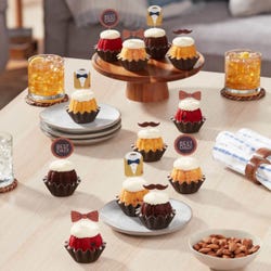 Cupcake-sized mini cakes with frosting and topped with bowties