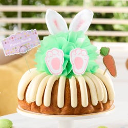 A bunny bundt cake with a mint colored bow in the center. Decorated with plush bunny rabbit ears