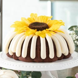 10 in bundt cake with signature frosting and topped with red rose flower.