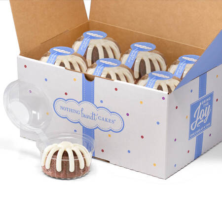 A dozen Bundtlets individually wrapped in decorative Nothing Bundt Cakes a box.