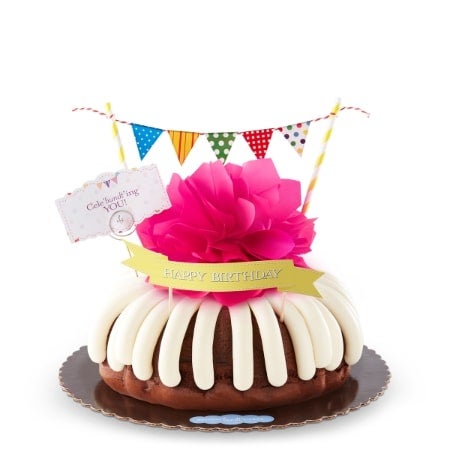 Celebundting You Bundt Cake with cream cheese frosting, pink paper bow, celebratory flags and celebundting you sign.