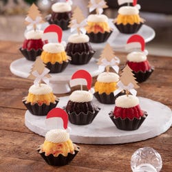 Each Bundtini® is adorned with a festive topper: two feature silver Christmas tree decorations and the other two have red Santa hats.
