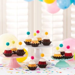 Cupcake sized bundt cakes in a variety of flavors with a pom pom topper. 