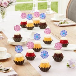 Bundtinis® topped with frosting and decorated with purple and pink flowers.
