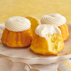 Lemon flavored mini bundt cakes topped with a cream cheese frosting swirl.