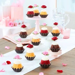 Cupcake sized bundt cakes in a variety of flavors with a pink and red rose toppers