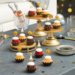 Mini Bundt cakes adorned with festive party hat toppers and golden pom-poms themed for a New Year's celebration.