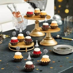 Mini Bundt cakes (Bundtinis®) each topped with creamy white frosting and adorned with silver party hats and matching silver pom-poms.