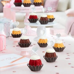 Four mini Bundt cakes each adorned with a delicate white heart topper